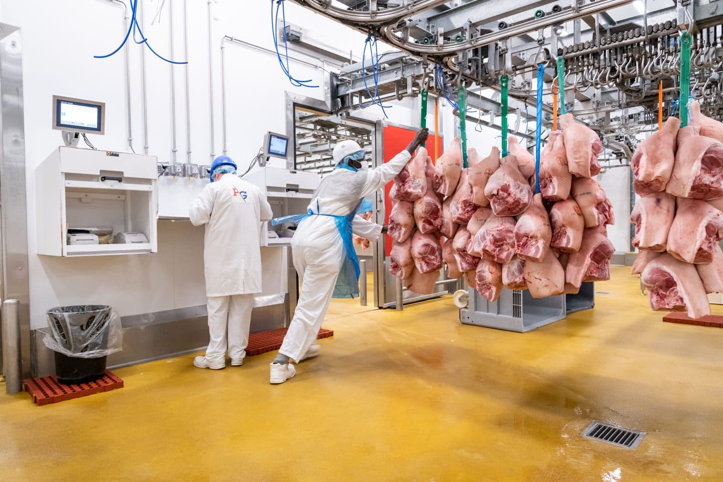 Grossistes qui déplacent leurs carcasses de viande sur les rails du pavillon de la viande