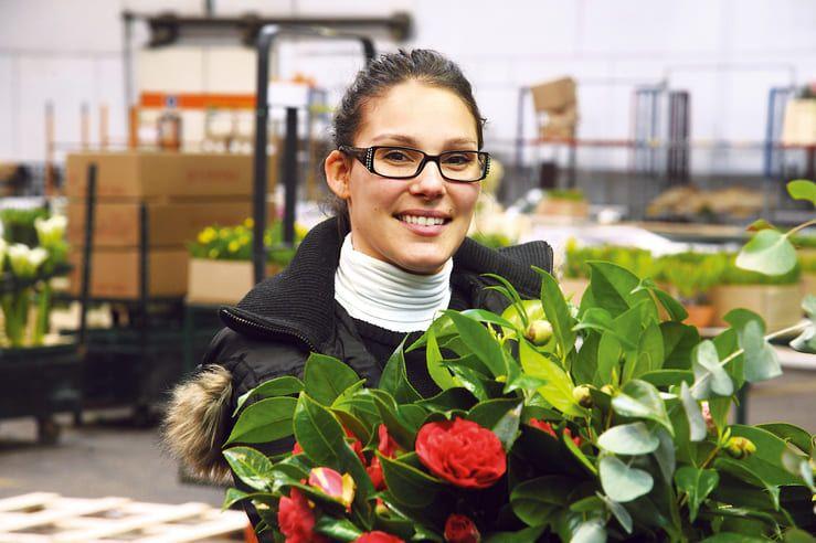 Acheteuse souriante tenant un pot de fleurs au Marché de Rungis